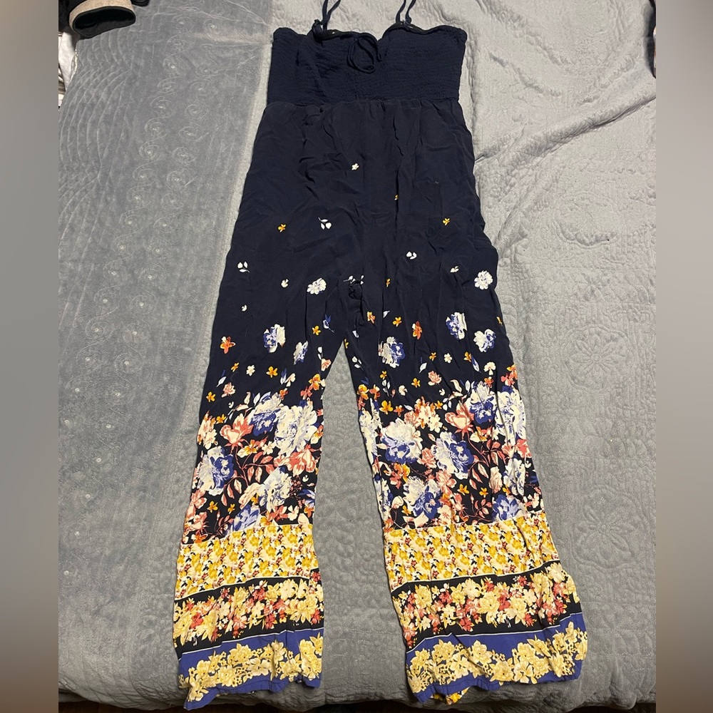 Jumpsuit w/ floral pattern. Slit flare cuffs. Smocked top.